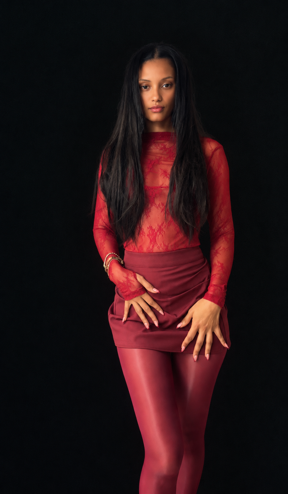 MONIKI in a crimson look against a dark backdrop